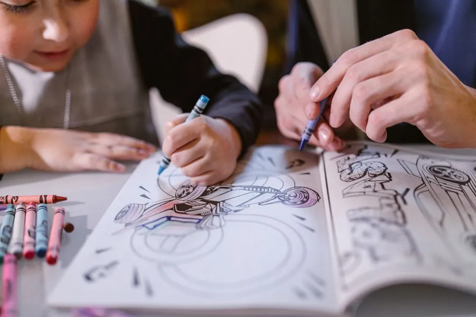 Child concentrating while coloring a page with crayons